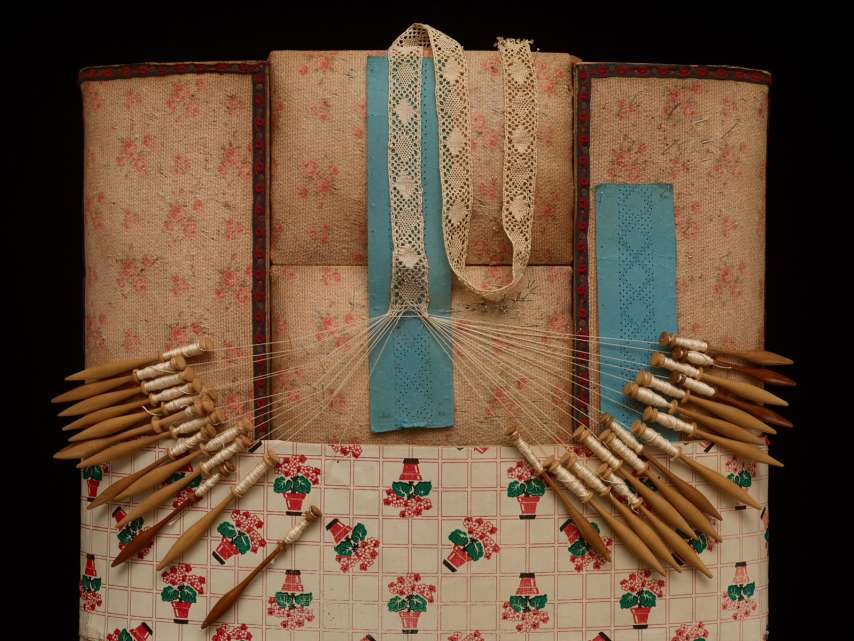 Klöppelkissen in Arbeit mit Klöppelbriefen und Holzklöppeln